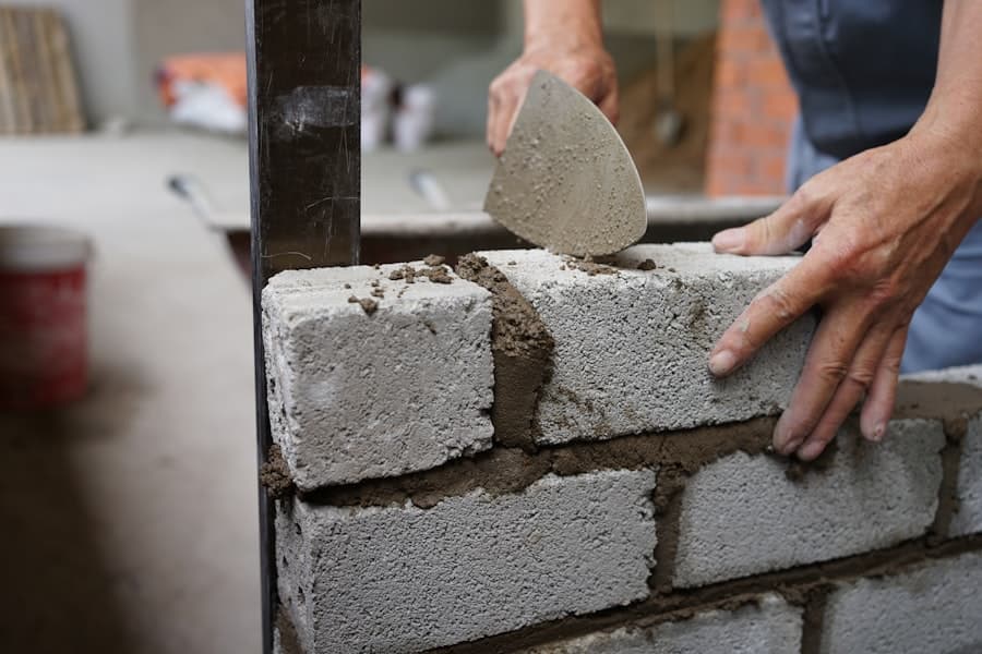 Mason laying a CMU block with mortar and a guide line