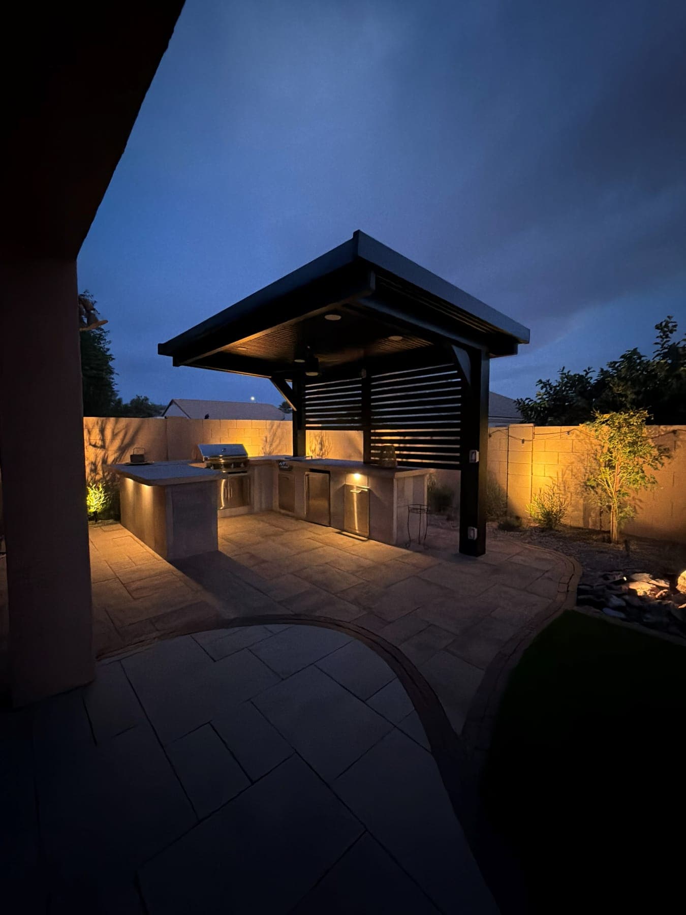 Shade structure with outdoor kitchen at dusk